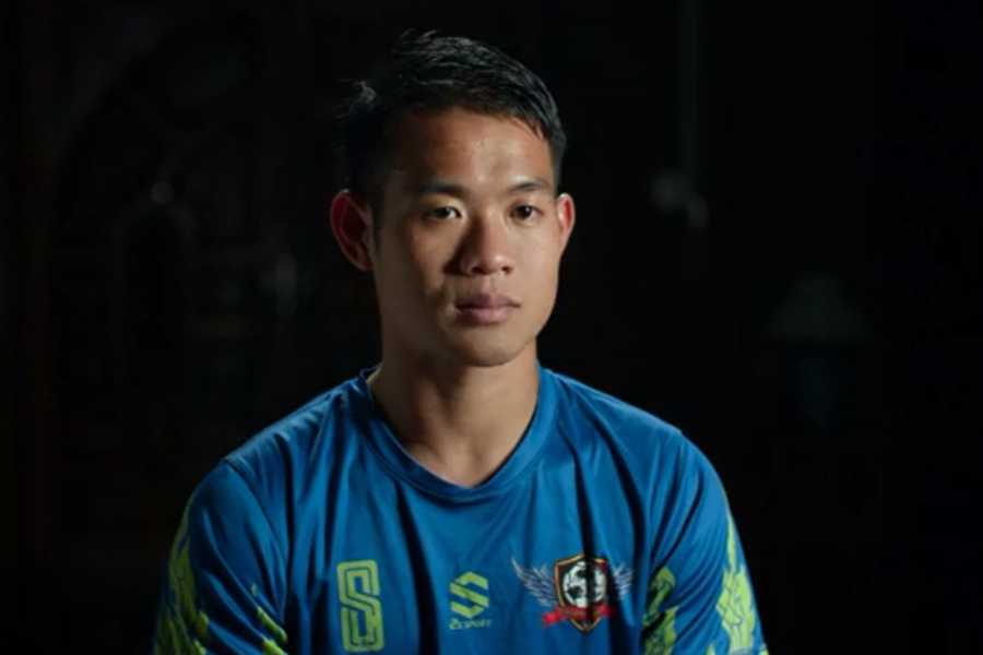 A young man in a blue sports jersey with green accents sits for an interview against a dark background. He looks composed and reflective, suggesting he is recounting a serious or emotional experience, possibly related to a rescue or survival story.