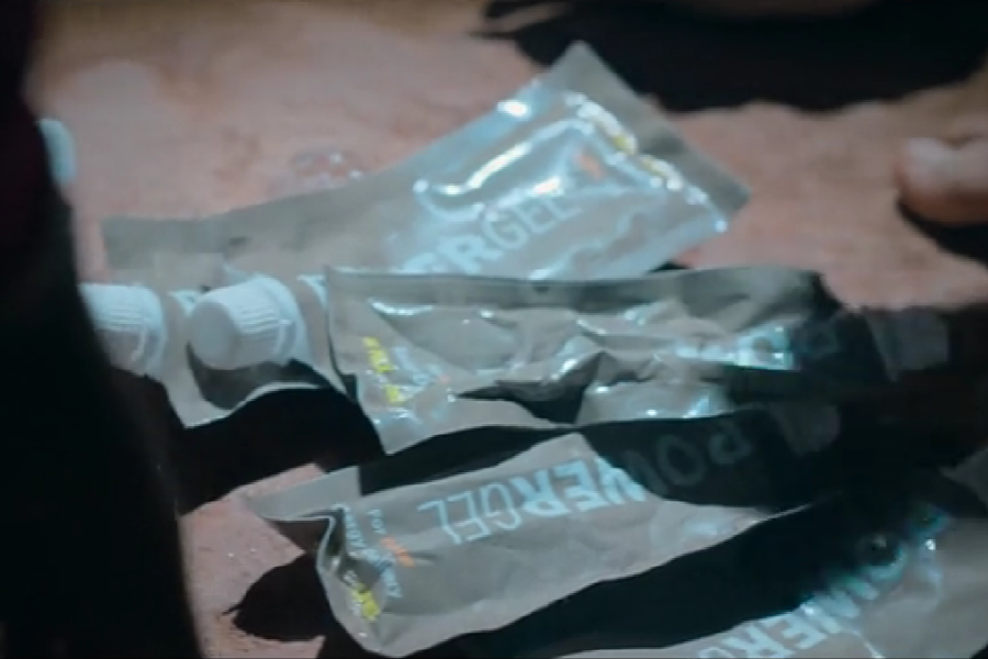 A close-up of several used energy gel packets labeled “POWERGEL” lying on the cave floor, likely consumed by trapped individuals or rescuers for quick nutrition. The image emphasizes the survival conditions and resourcefulness during the rescue effort.