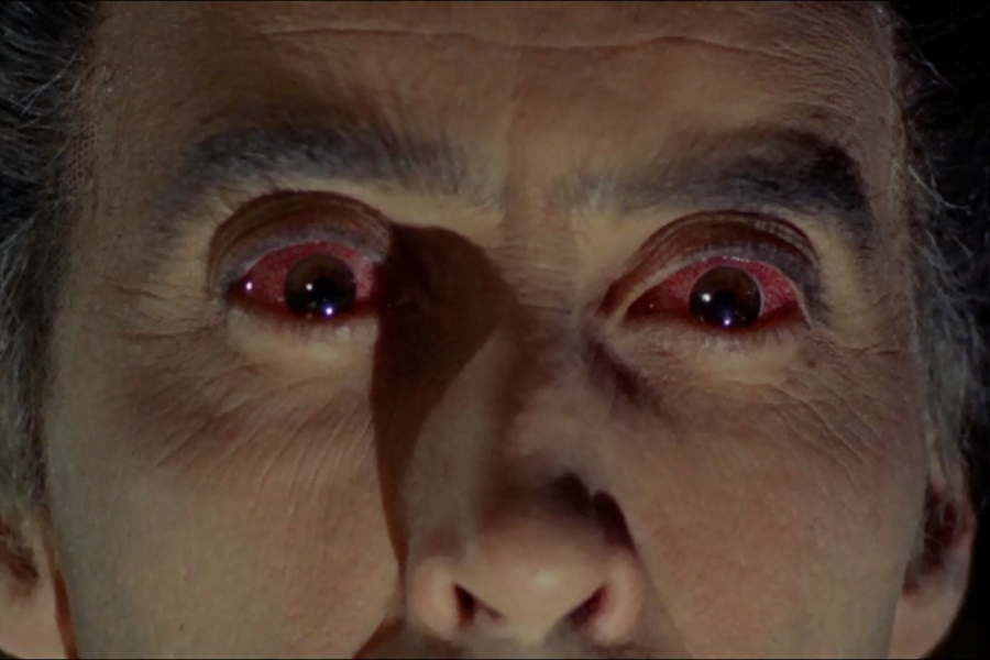 Close-up of a person’s face with intense, wide-open eyes that have unnaturally red sclera and dark pupils, creating a dramatic and eerie appearance. The skin appears pale and the lighting emphasizes the facial details.