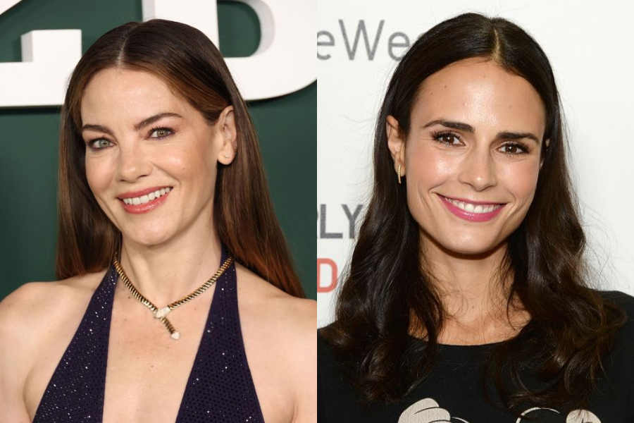 Side-by-side photo of two women with long dark hair smiling at the camera. The woman on the left wears a dark halter dress and gold necklace against a green backdrop, while the woman on the right wears a black top with a graphic print against a white backdrop with text.
