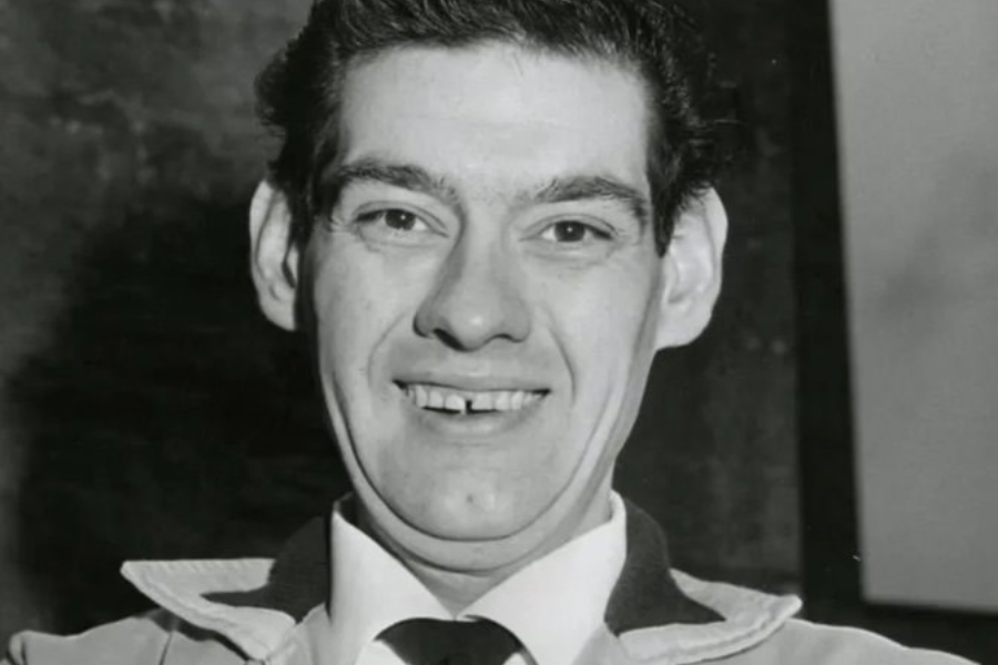 Portrait of a smiling man in a collared shirt and jacket, showing his face post-weight loss with a relaxed expression.