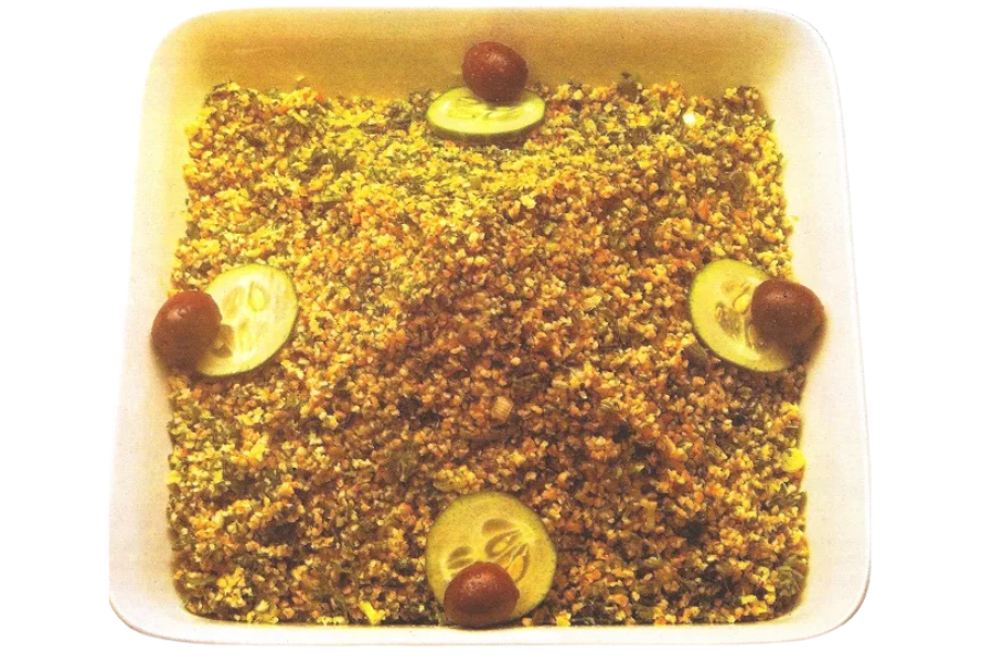 A rectangular casserole topped with finely chopped meat and vegetables, garnished with cucumber slices and cherry tomatoes at the corners.