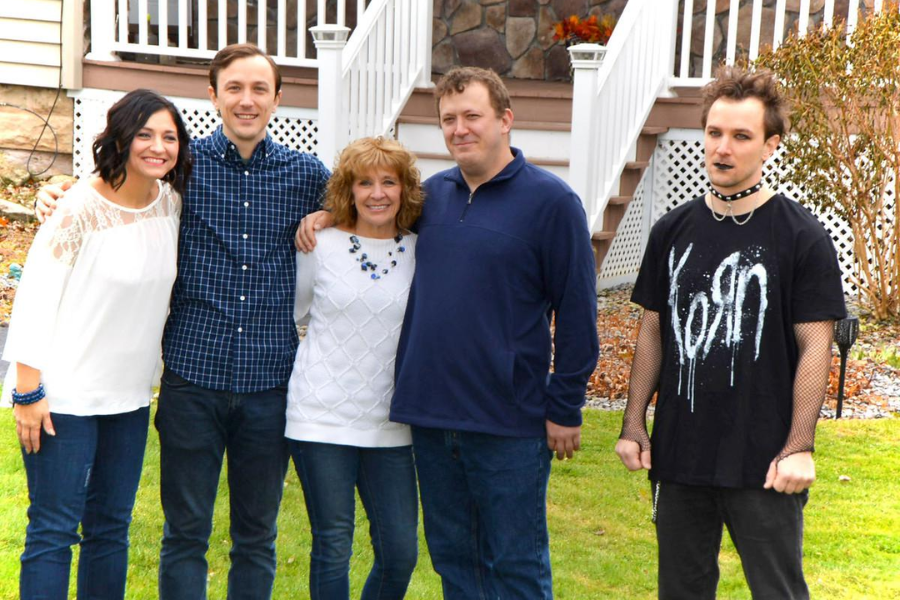 A cheerful family poses together in coordinated blue and white, while a gothic teen in a black Korn shirt stands off to the side, looking disconnected.