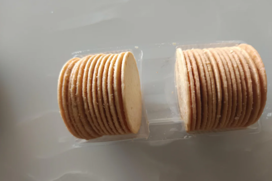 Two stacks of uniformly thin round crackers in a clear plastic tray, with visible space between them suggesting underfilled packaging.