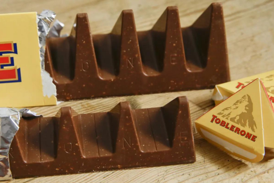 Two Toblerone chocolate bars with noticeably wider gaps between the triangular pieces than usual, with branded packaging in the background.