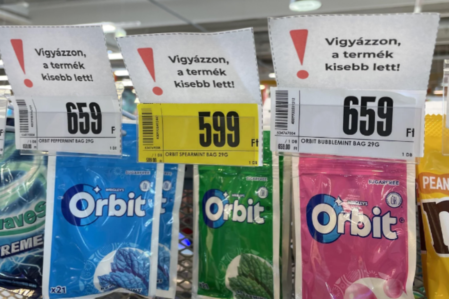 Orbit gum pouches on store hooks in Hungary with signs that translate to “Warning, the product got smaller” displayed above the prices.