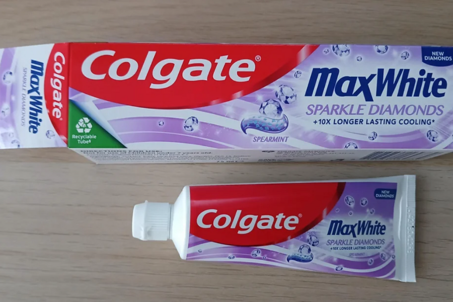 A tube of Colgate MaxWhite Sparkle Diamonds toothpaste appears significantly smaller than its box, creating an illusion of more product.
