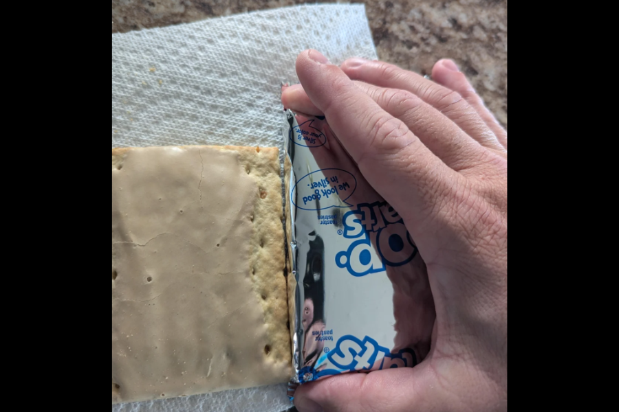 A Pop-Tart partially unwrapped on a paper towel next to its foil wrapper, revealing a smaller size than expected compared to the packaging.