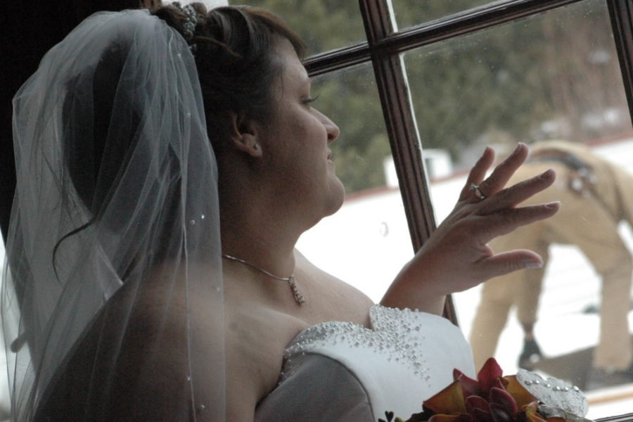 A bride in her gown gazes out the window wistfully, her pose dramatically overshadowed by a man outside accidentally showing his butt.