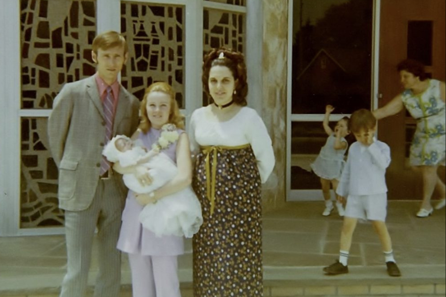 A vintage family photo in front of a church is photobombed by kids mid-chaos and a woman chasing after them in the background.