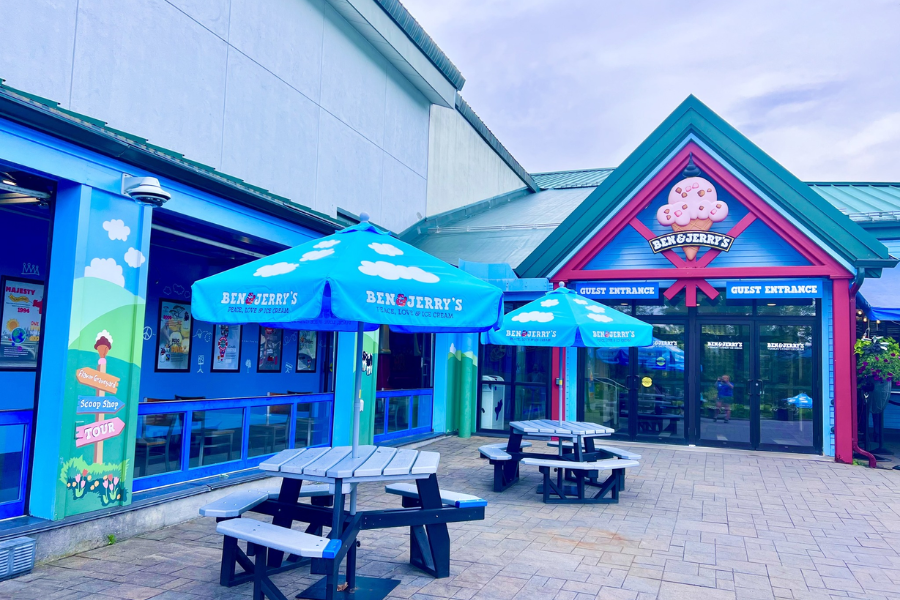 The entrance to the Ben & Jerry’s Factory in Vermont is decorated with playful blue and pink colors, cartoon cows, and branded umbrellas over picnic tables.