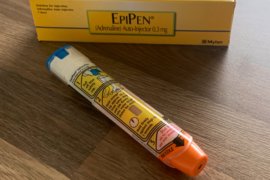 EpiPen 0.3mg adrenaline auto-injector lying on a wooden table next to its yellow instruction-labeled box.