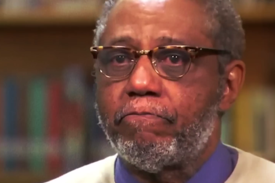 Close-up of a man wearing glasses with a solemn expression, eyes appearing teary.