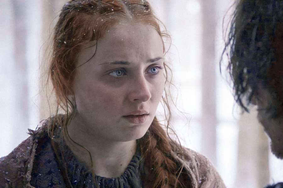 A red-haired young woman with snowflakes in her hair stares intensely at someone off-screen in a wintry setting.