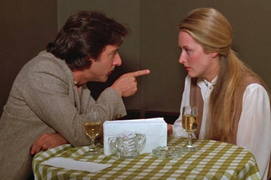 A man angrily points his finger at a woman across a small table during a heated conversation in a restaurant.