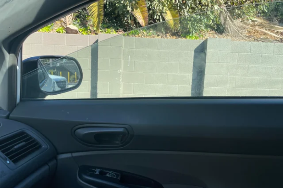 Partially rolled-down car window showing a clean outline of the glass contrasted against dust on the rest of the pane.