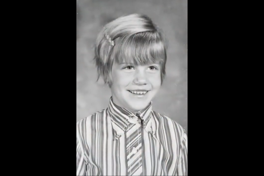 Black and white school portrait of a young child with short hair, smiling and wearing a striped shirt.