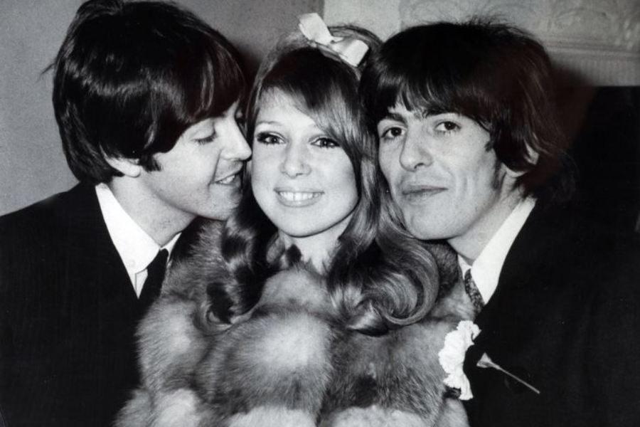 Paul McCartney leans in playfully toward Pattie Boyd as she smiles beside George Harrison on their wedding day.