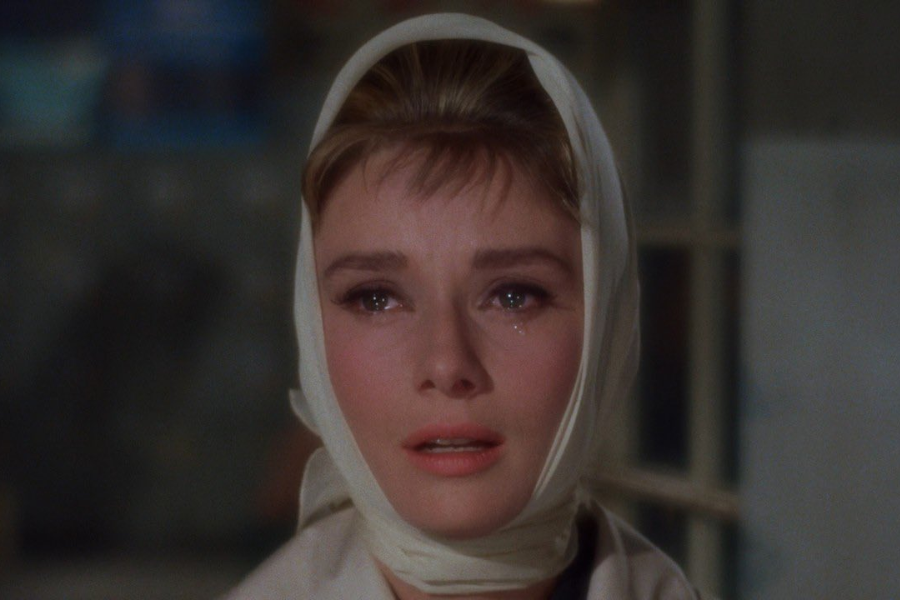 A tearful woman with a white headscarf looks heartbroken under soft lighting, her eyes glistening with emotion.
