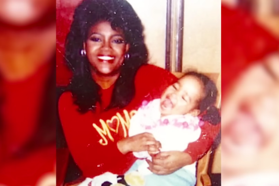 A smiling woman in a red sweater holding a laughing baby girl in her arms, both radiating joy.