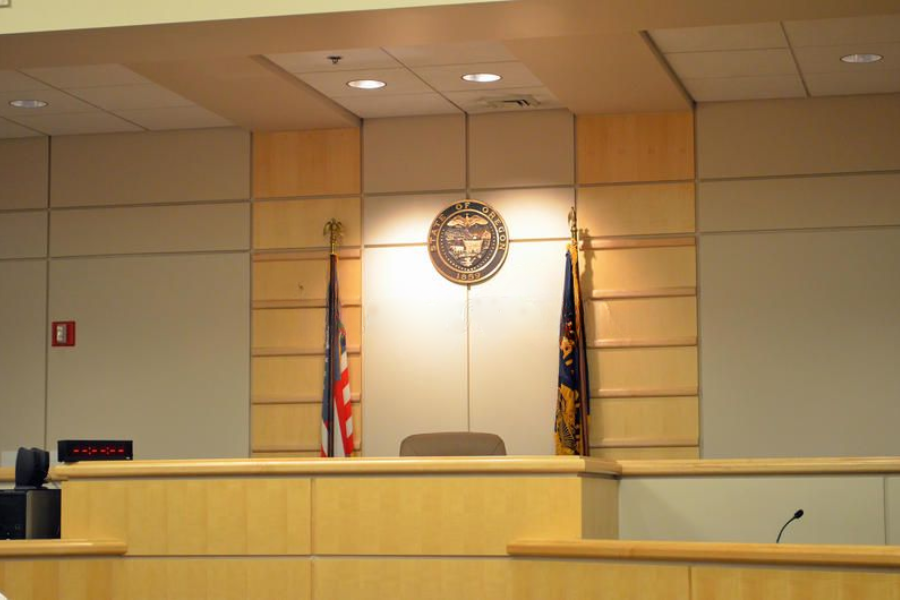 An empty courtroom with the seal of the State of Ohio, U.S. and state flags behind the judge’s bench.