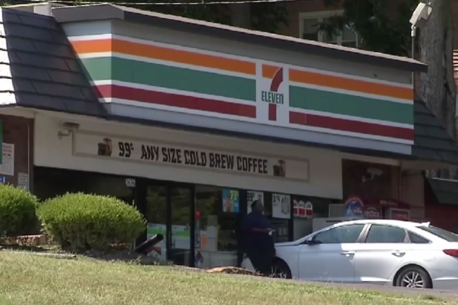 Exterior of a 7-Eleven convenience store with a sign advertising 99¢ cold brew coffee and a customer walking in.