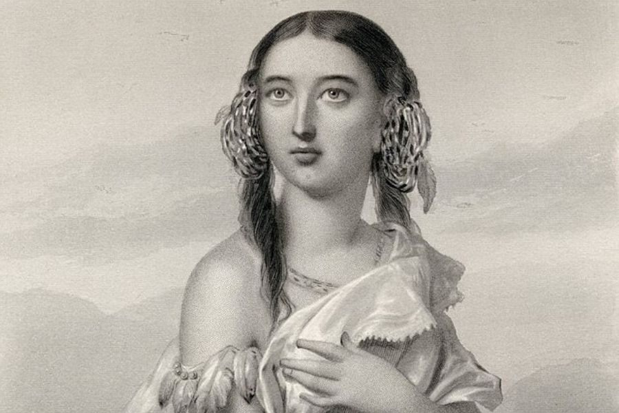 A sepia-toned portrait of a woman wearing a flowing dress with an off-shoulder design. She has long hair adorned with braided details, gazing thoughtfully upwards against a soft, blurred background. The mood is serene and contemplative.