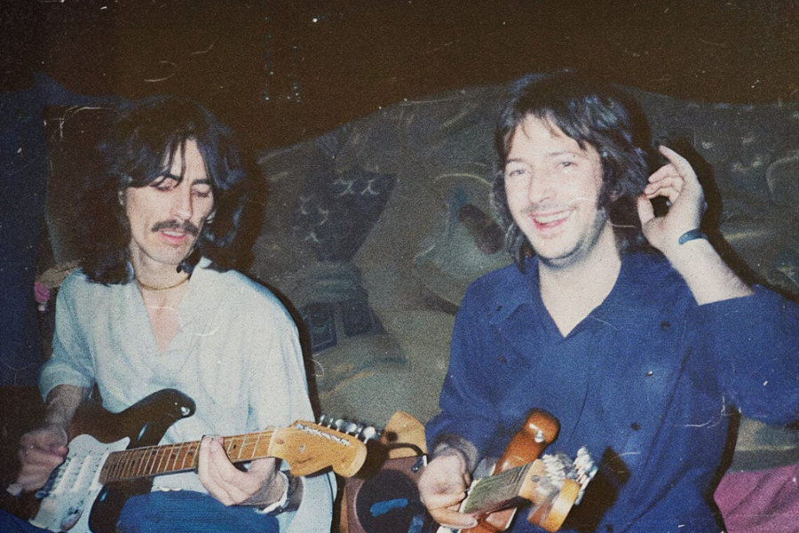 George Harrison and Eric Clapton laughing and playing electric guitars in a warmly lit room with a vintage vibe.