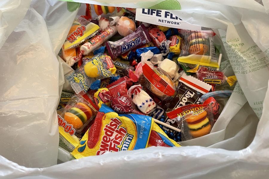 A plastic bag filled with assorted candies including Swedish Fish, Tootsie Rolls, Laffy Taffy, and Smarties.