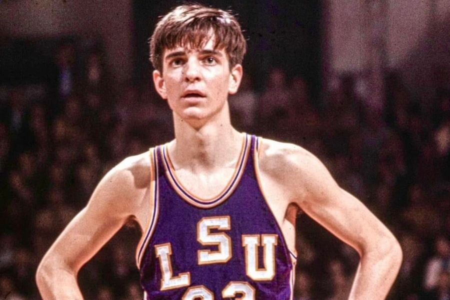 Young basketball player in a vintage "LSU 23" jersey stands with hands on hips, looking focused. Background is a blurred crowd, conveying an intense atmosphere.