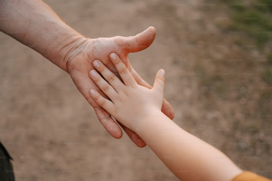 The hand of a child being held by the hand of an adult. 