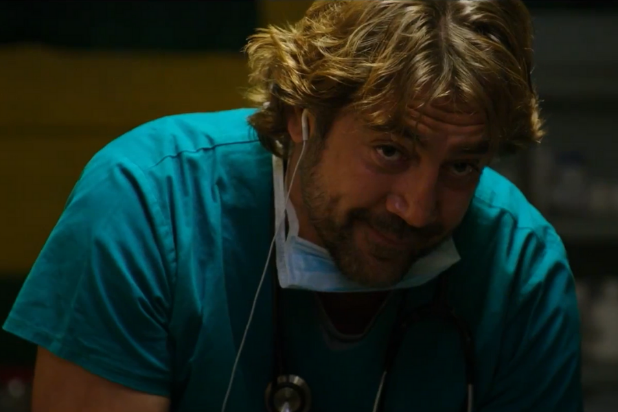 A man in scrubs with a stethoscope and surgical mask peers intently, seemingly focused. The lighting is dim, creating a serious, intense mood.