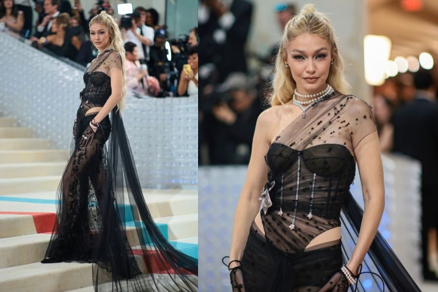 model walks the Met Gala steps in a sheer black corset gown with star embellishments and long tulle train, accessorized with pearls.