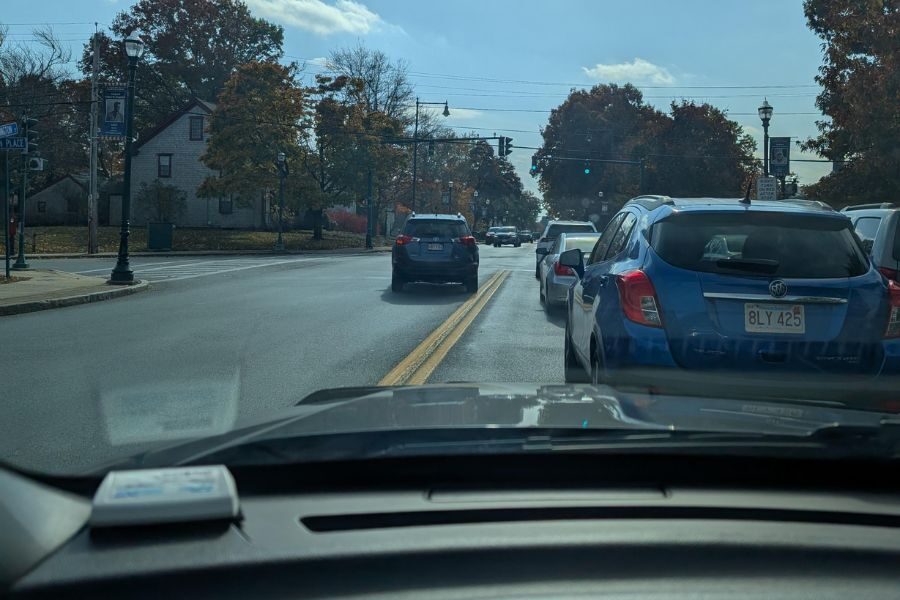 View from inside a car approaching an intersection with double yellow lines and several vehicles ahead.