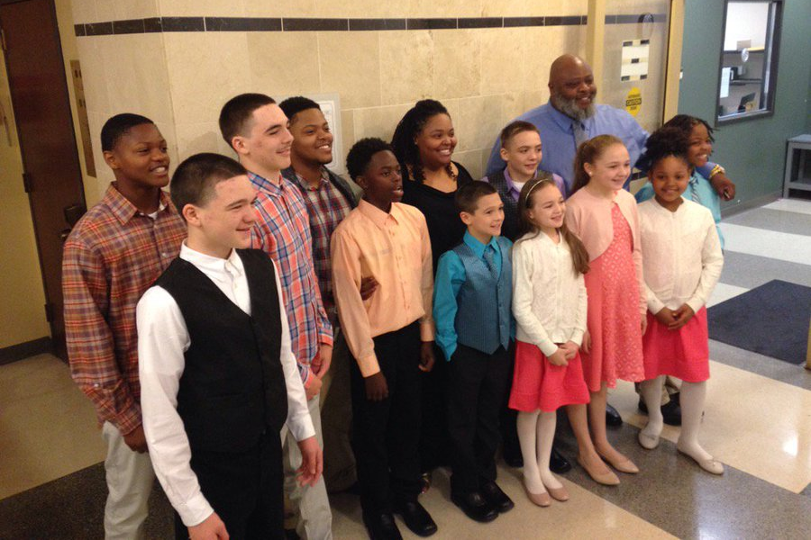 A large, smiling family group dressed in formal attire, posing together in a public building lobby.