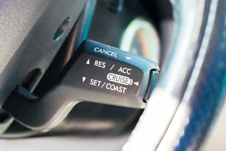 Close-up of a cruise control lever on a steering wheel with options labeled cancel, resume, accelerate, set, and coast.