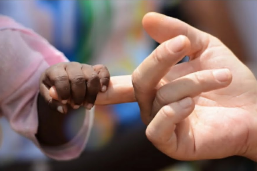 A close-up of a small child’s hand grasping an adult’s finger in a tender, symbolic gesture.
