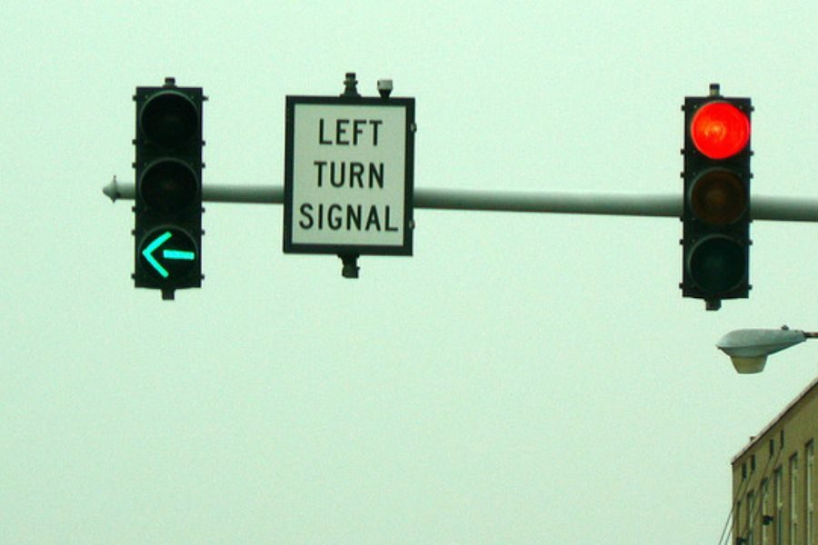 Traffic signal with a green left arrow and a red light, accompanied by a sign reading “Left Turn Signal.”