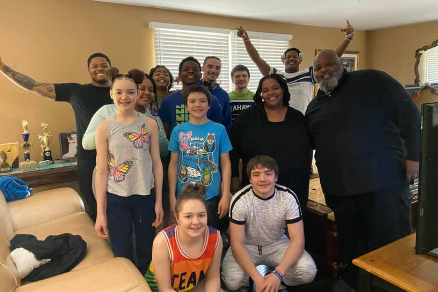 A blended family of thirteen posing happily in a living room, with two members sitting and others standing behind them.