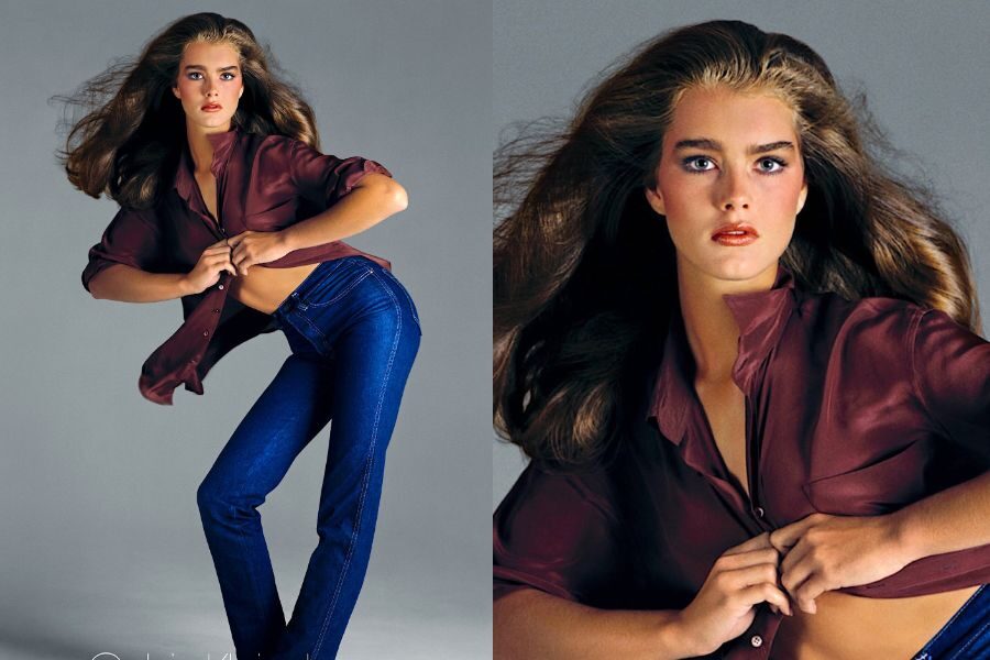 A young model in high-waisted jeans and an open burgundy blouse poses with dramatic hair and intense expression.