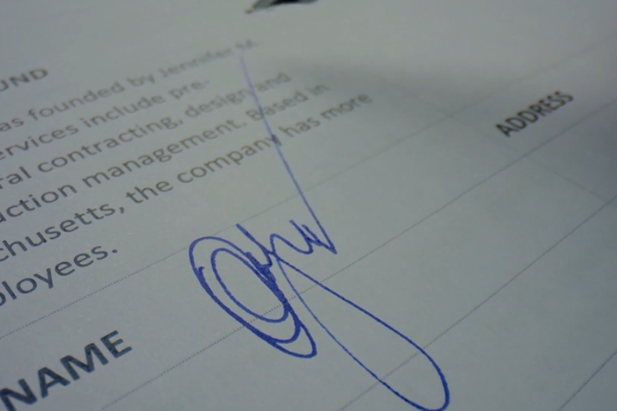 A close-up of a handwritten signature in blue ink on a formal document, with the word "NAME" visible.