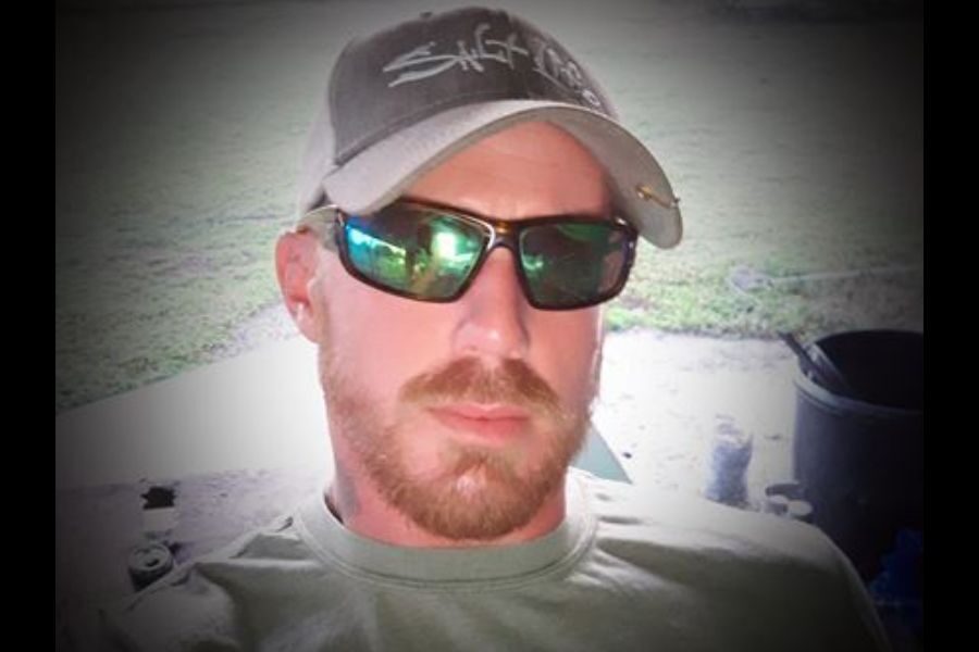 Portrait of a white bold man wearing a hat and dark sun glasses