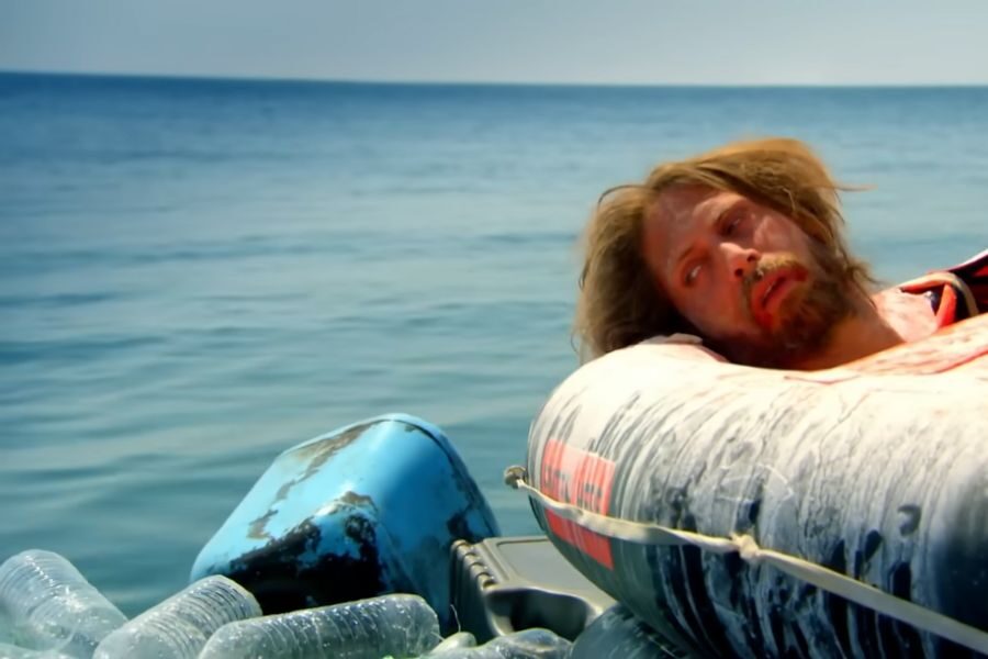 A weary man with disheveled hair lies on an inflatable raft, looking exhausted. Surrounded by the sea and plastic bottles, evoking a sense of isolation.
